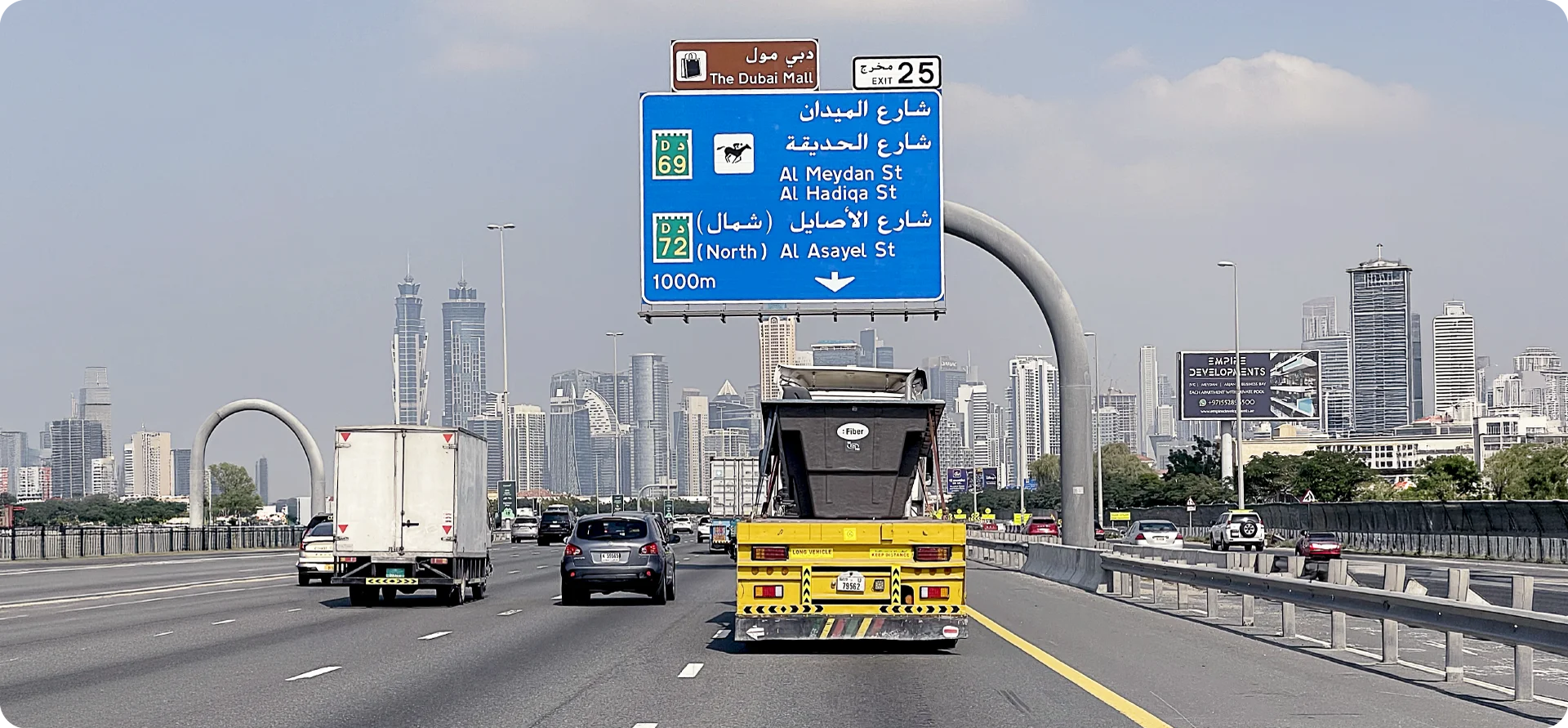 Rodovia em Dubai com placa em árabe e skyline ao fundo, representando a expansão internacional da Fiber